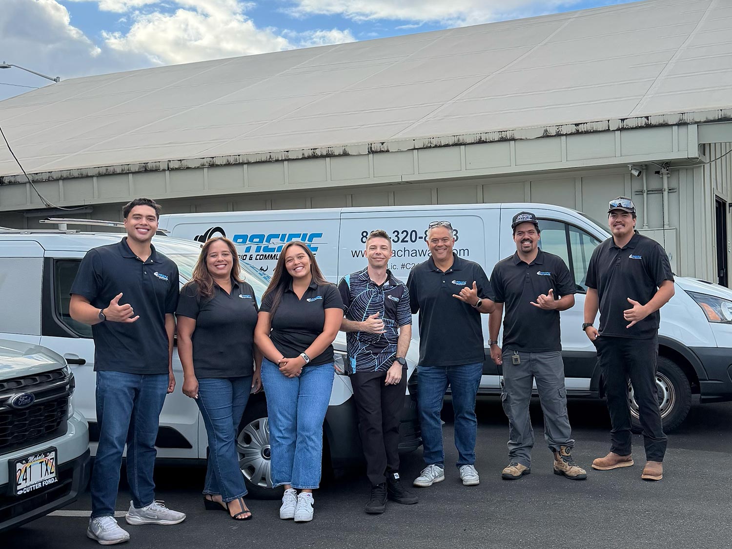 Seven team members standing together in front of a white work van parked outside