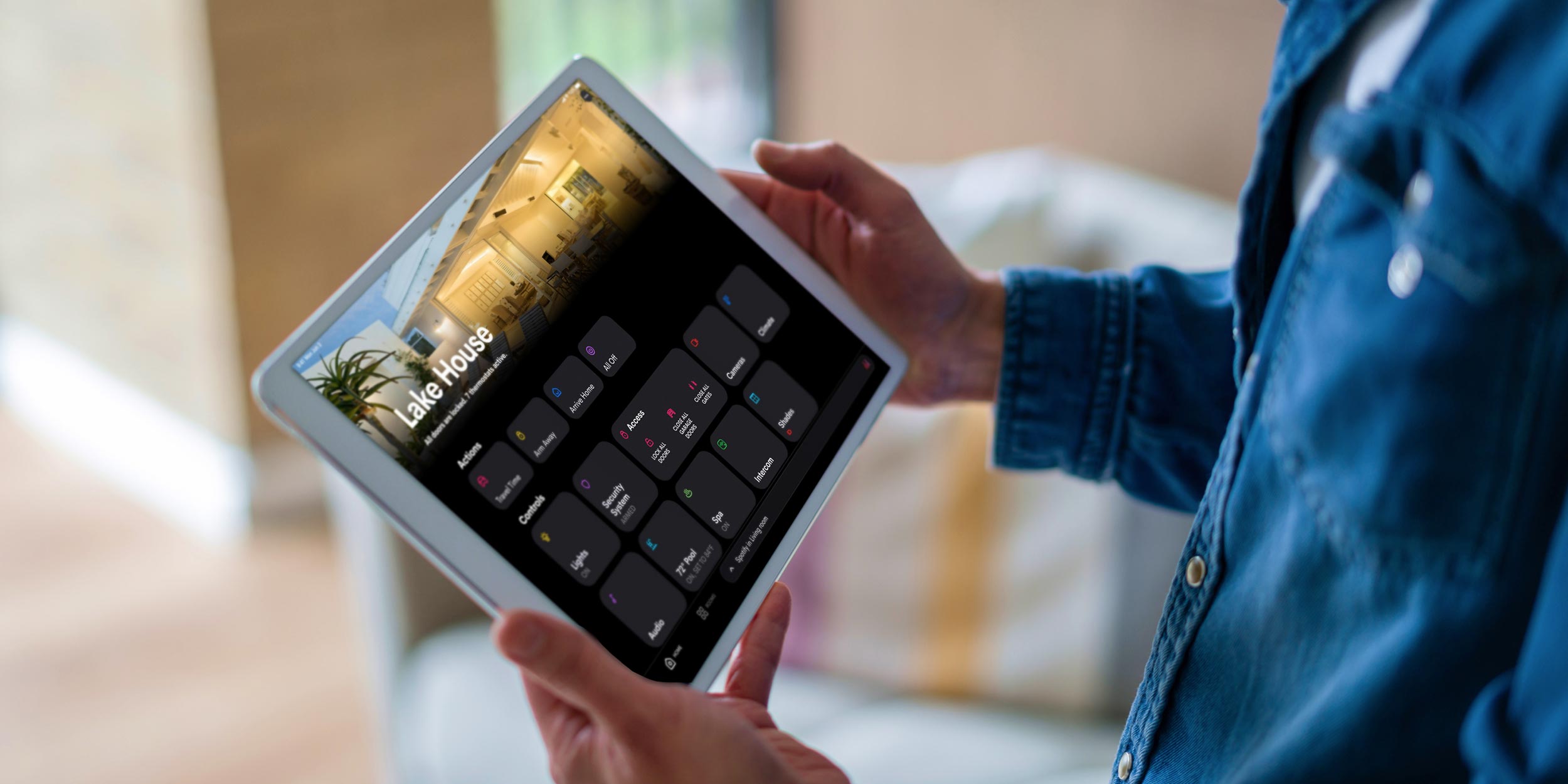Person holding tablet showing home automation controls labeled Lake House