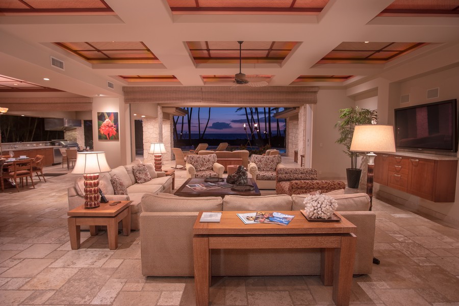 A living room and kitchen with an open concept design looking out into a view of the beach.  