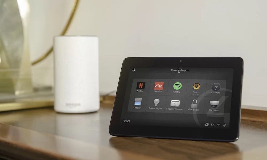 Photo of a Control4 home automation tablet sitting on a counter with a white smart speaker behind it.