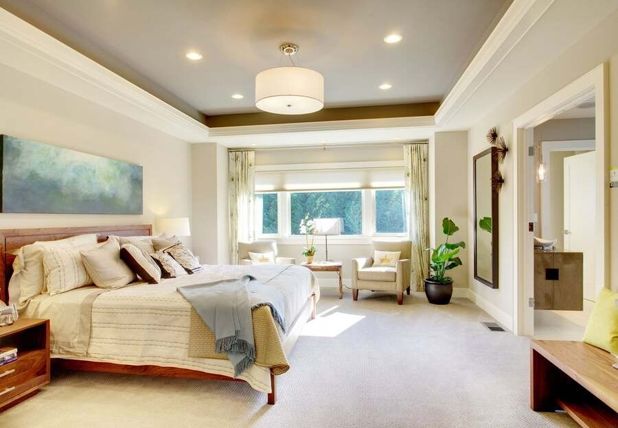 An elegant bedroom illuminated by recessed lighting fixtures.
