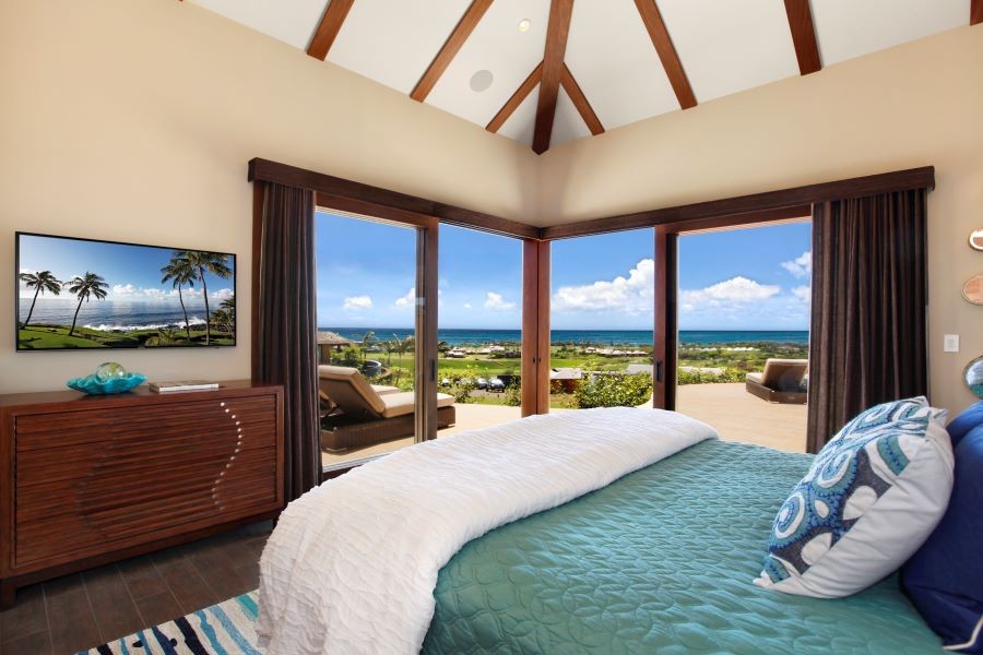 A bedroom with drapes pulled back, offering an ocean view.