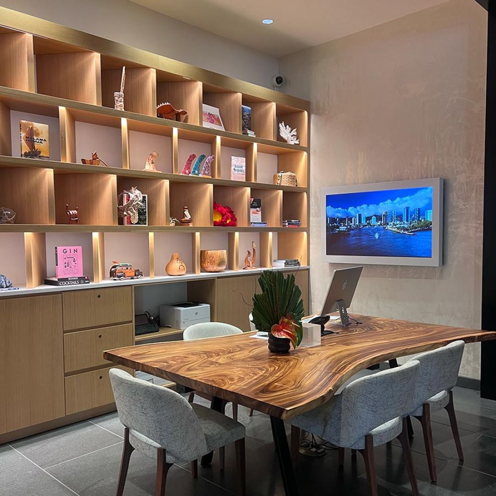 Meeting room with wood table, built-in shelving, decorative objects, and wall-mounted screen