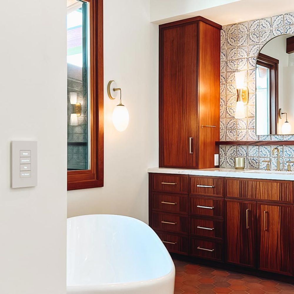 Modern bathroom with wood vanity, patterned tile wall, and freestanding bathtub