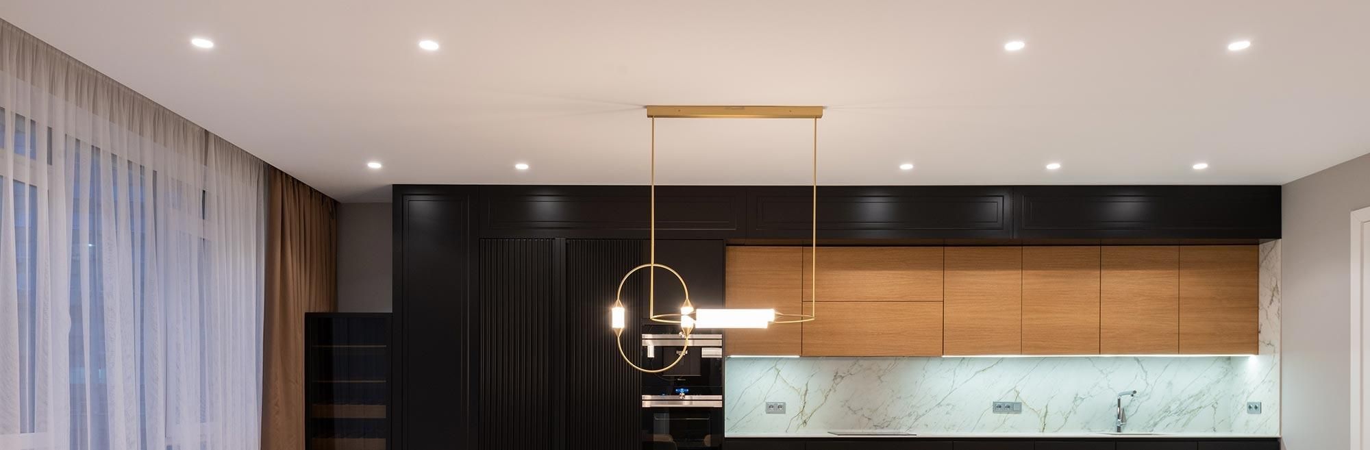 Modern kitchen with sleek downlighting, wooden cabinets, and marble backsplash.